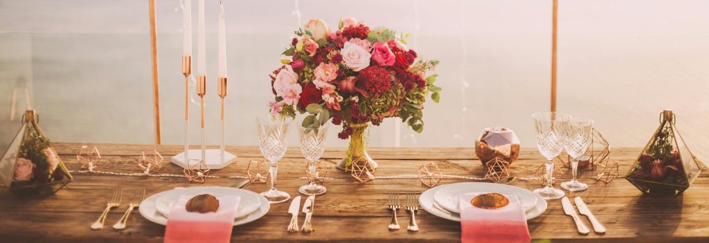 pexels-photo-1045541-1045541 Romantic dining setup with flowers and candles overlooking Santorini waterscape at sunset.